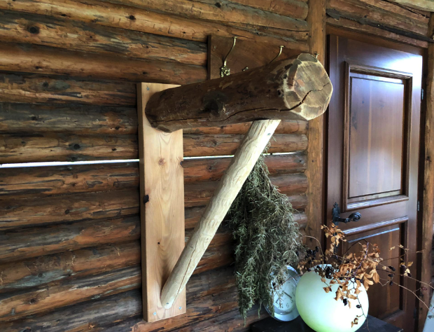 Handgefertigte Sattelaufhängung aus Naturholz an einer Blockhauswand